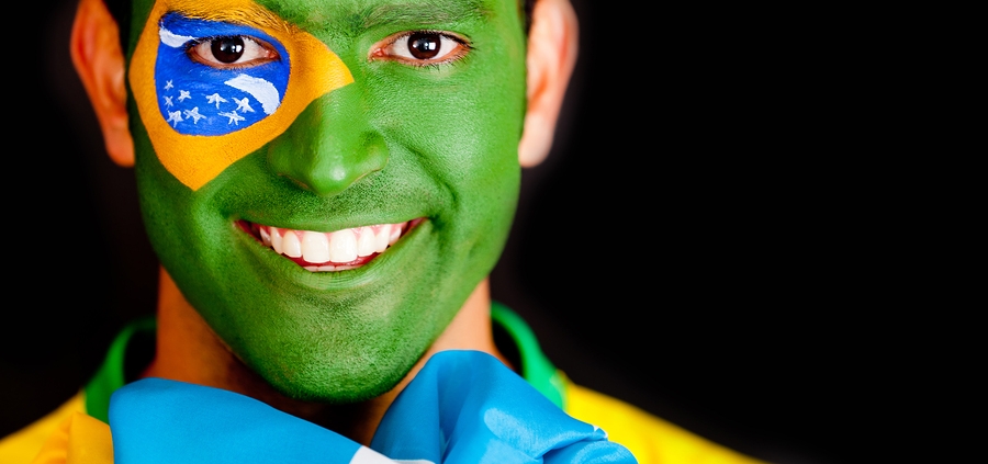 Smiling young man whose face is painted like the Brazilian flag